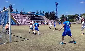 Fußballspiel im demolierten Stadion, rechts im Hintergrund das zerstörte Tschernihiw-Museum für ukrainische Altertümer, Juni 2022