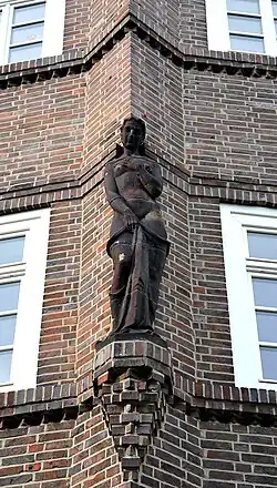 Spärlich bekleidete Frau mit Textilie auf kielförmigem Erker im Stil des Backsteinexpressionismus