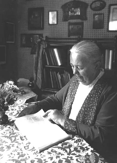 Aufnahme von Anna Bernard im Heimathaus in Bad Kudowa, sitzend am Wohnzimmertisch