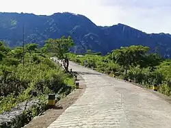 Auf einer Straße mit dem Foho Malitoli im Hintergrund