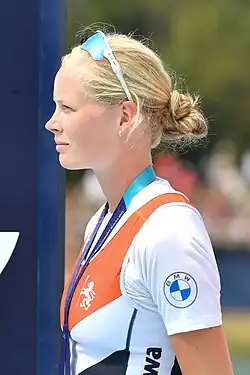 Ilse Kolkman schaut bei der Siegerehrung nach rechts. Sie trägt das niederländische Nationaltrikot über einem weißen T-Shirt. Um den Hals hängt ein blaues Band, an dem die nicht sichtbare Silbermedaille befestigt ist. Ihre Sonnenbrille hat sie hochgeschoben.