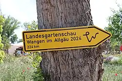 Wegweiser auf der Bundesgartenschau 2023 im Mannheimer Spinelli-Park im Stil eines Straßenschildes auf die 2024er Veranstaltung in Wangen mit Entfernungsangabe 224 km