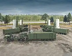 Eine Typhon-Batterie mit vier Startgeräten und einem Kommandofahrzeug wird auf einem Feld ausgestellt.