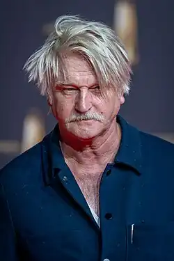 Detlev Buck mit verwuscheltem weißen Haar auf rotem Teppich