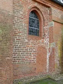 Altes Mauerwerk in der Nord­wand des Chors, Korb­bogen der Priester­pforte wohl etwas neuer, Innen­stufe des Fenster­gewändes und unterste 10 Stein­reihen ersetzt.