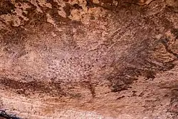 Gefleckte Giraffe. Umrisszeichnung mit dunklen Punkten auf dunklem Felshintergrund.