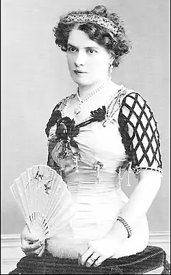 Antonia Matt um 1900: eine elegant gekleidete Dame mit eng geschnürter Taille und einem Fächer sitzt auf einem Kissen. Man sieht, dass sie keine Beine hat