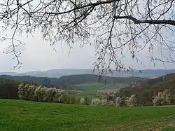 Blick von Böllstein (Wallbrunn) über Gneis-Hügel (rechts: Schnellerts, links: Eichberg-Rücken) und das Gesprenztal zum Flasergranitoid-Höhenzug Neunkircher-Höhe-Nonrod, links davon: Lindenfelser Granit-Diorit-Gabbro-Berge (Schenkenberg, Das Buch)
