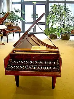 Bach-Cembalo mit mittelbraunem, flügelförmigen Gehäuse, aufgeklapptem Deckel und sichtbaren Saiten sowie filigraner Klaviatur in zwei Tastenfeldreihen im Musikinstrumenten-Museum Berlin