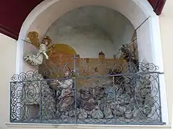 Die im unteren Teil von einem Rankengitter abgeschlossene Nische der Ölberggruppe. Die Jesusfigur blickt zu einem über ihm schwebenden Engel, während Jesus’ Jünger hinter ihm schlafend liegen. Die Rückwand der Nische ist mit der Darstellung eines großen, sandfarbenen Gebäudes bemalt.