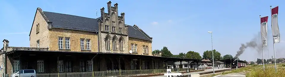 Historisches Bahnhofsgebäude in Quedlinburg mit Bahnsteig und Dampflok, die Rauch ausstößt