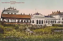 Straßenseite des Stadtbahnhofs Banja Luka mit Park und Holzpavillon als schattenspendende Sitzgelegenheit