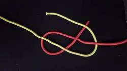 Jetzt geht es immer unter, über, unter, über, usw. weiter. Das heißt, man führt das gelbe Ende unter das (rote) feste Ende oder auch stehende Part genannt und über das rote lose Ende, auch lose Part genannt.