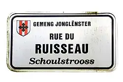 Zweisprachiges Schild in Junglinster: Schoulstrooss / Rue du Ruisseau (franz. für Bachstraße)