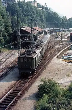 144 507-1 rangiert im Mai 1980 mit einer Schwestermaschine ein paar Reisezugwagen im Bahnhof, bevor sie den E 799 (ab Freilassing: D 799) nach Kassel übernehmen. Links ist der Lokschuppen und im Hintergrund sind die Ladegleise für den Güterverkehr zu erkennen.