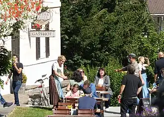 Dreharbeiten am „Wilden Kaiser“ in Going für die 14. Staffel: Natalie O’Hara (Susanne Dreiseitl), stehend, Heiko Ruprecht (Hans Gruber), am Tisch sitzend mit Ylvi Unertl (Sophia Gruber).