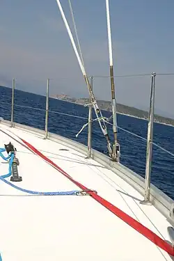 Das Bild zeigt ein Schiffsdeck mit einem roten Gurtband, an dem man sich einhaken kann, und eine Reling, an der man das nicht tun sollte.