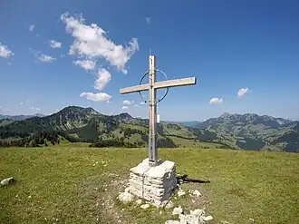 Brünnsteinschanze, Gipfelkreuz. Im Hintergrund Traithengruppe (links) und Wendelstein (rechts).