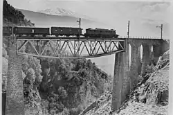 Be 6/8 der BLS um 1930 auf dem Baltschiederviadukt, einem mit einer Fachwerkbrücke verbundenen Steinbogenviadukt. Hinter der Lokomotive ein dreiachsiger Postwagen mit Oberlicht, gefolgt von einem dreiachsigen Gepäckwagen.