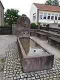Brunnen an der Bruder-Klaus-Kirche, rechts ehemaliger Kindergarten von Niedergailbach