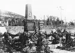 Auf dieser Fotografie in schwarz-weiß ist die Grabstätte mit vielen Pflanzen und Blumen zu sehen.