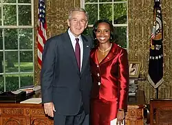 George W. Bush mit La Celia Aritha Prince, der Botschafterin von Saint Vincent und den Grenadinen in einem Empfangszimmer des Weißen Hauses in Washington vor zwei Flaggen.