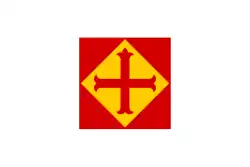 Rotes Quadrat, indem sich eine gelbe Rombe mit rotem Kreuz befindet; die rechteckige Grundfläche ist weiß