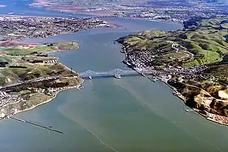 Luftaufnahme der Carquinez-Straße mit der Carquinez-Brücke im Vordergrund, der Benicia–Martinez Bridge in der Ferne; in der Mitte die Halbinsel am Dillon Point mit dem Mast am Ort der ersten Freileitungskreuzung