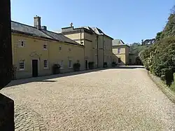 Links: Auffahrt von Castle Hill von unterhalb des Einfahrtsbogens mit Blickrichtung nach Westen zu den schmiedeeisernen Ziertoren zum Innenhof; Flügel für Dienerschaft rechts. Rechts: Nordfassade und Haupthof, gesehen von westlich der Tore des Hofes vor dem Flügel für die Dienerschaft hinter diesem Flügel.