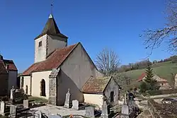 Kirchengebäude mit blauem Landschaft und Himmel am Horizont und seitlich befindliche Gräber.