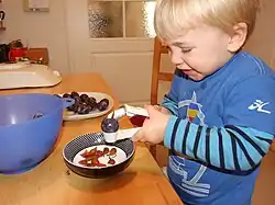 Kind beim Entkernen einer Zwetschge