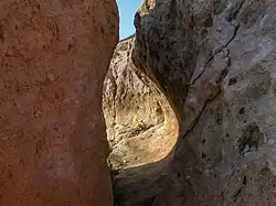 Links: Etwa vier Meter hoher Stumpf des Kliffs des ersten Stadiums mit Brandungshohlkehlen. Rechts: Blick in die obere Brandungshohlkehle durch den Spalt in der oberen Bildmitte des linken Bildes hindurch.