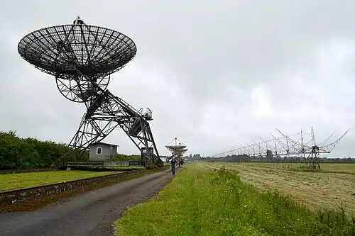 Eine Antenne des One-Mile Telescope (links), zwei Antennen des Half-Mile Telescope (Mitte) und Reste des 4C Array (rechts)