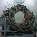 Die Gantry mit abgenommenem Gehäuse: „D“ markiert den Detektorkranz, bei „T“ befindet sich die Röhre (englisch Tube), die ihren Fächerstrahl in Richtung der roten Linien abgibt. „R“ markiert die Rotationsrichtung von Röhre und Detektor.