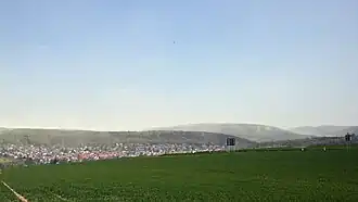 Blick von einem Fahrweg nahe der Kreuzung der Kreisstraßen 4 und 6 südwestlich von Nieste über das Dorf im Niestetal hinweg ostnordostwärts zum Haferberg; rechts der Berg Mühlenstein