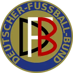 Abgebildet ist das Logo des Deutschen Fußball-Bundes von 1900 bis 1945. Es stellt einen Freis dar, der in blau und gold gehalten ist. Am äußeren Rand wird der Schriftzug DEUTSCHER-FUSSBALL-BUND im Kreis geführt. In der Mitte befindet sich die Abkürzung „DFB“: Jeder Buchstabe in einer anderen Farbe, weiß schwarz und rot.
