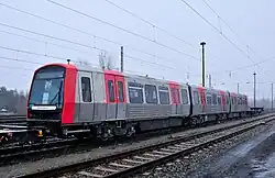 Zug der Baureihe DT5 der U-Bahn Hamburg auf Überführungsfahrt im Eisenbahnnetz, vorne und hinten je ein Kuppelwagen zwischen der U-Bahn-typischen Scharfenbergkupplung und der bei der Eisenbahn üblichen Schraubenkupplung mit Puffern