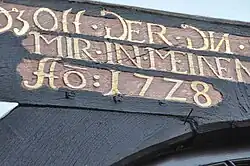 Teil eines Spruchbalkens mit der kontrahierenden Abbreviatur „Aō:17Z8“ (für „Anno [domini] 1728“, auf Deutsch: „Im Jahre des Herrn 1728“)
