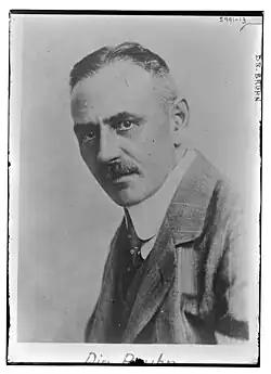 Mann mittleren Alters im Seitenprofil nach links vorne schauend ab Brustkorb im grauen Jackett, weißem Hemd und dunkler Krawatte in schwarzweiß.