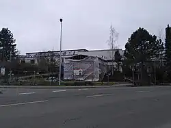 Mit Folie umschlossenes Gerüst hinter einem Bauzaun an hinter einer Straße