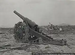 mächtiges mobiles Geschütz des Ersten Weltkrieges auf zwei großen Rädern inmitten von Holztrümmern