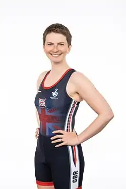 Erin Kennedy trägt ein dunkelblaues Trikot zu einer schwarzen Hose, im Hintergrund eine weiße Wand.