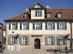 Rückwärtige Häuserzeile: Gemeindezentrum am Bahnhofplatz 2 (links) und Pfarrhaus am Bahnhofplatz 3 (rechts)