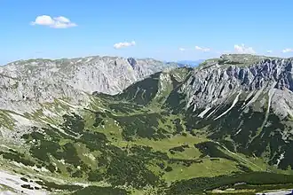 Blick vom Fölzkogel nach Nordosten über die Fölzalm zum Fölzsattel. Rechts die Wand der Mitteralm, hinten die Höllmauer.