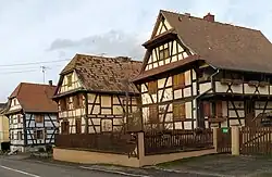 Typische Sundgauer Fachwerkhäuser in Rähmbauweise mit Wetterdächlein am Giebel, Laube mit Andreaskreuzen, das vorderste Haus ohne den im Sundgau üblichen Krüppelwalm