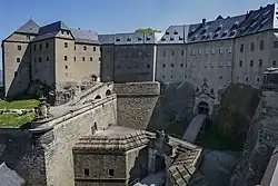 Toranlage aus verschiedenen Bauphasen.Links der Kernbau aus dem Mittelalter (Georgenburg, umgebaut 1605), davor die „Ge­or­genbatterie“ 1669, rechts Er­weite­rungen 1589–1591 (Streich­wehr u. zwei­mal geknicktes Torhaus), vorn Graben;schere aus dem 18. Jh.