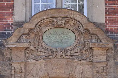 Relief direkt über dem Eingang mit Sinnspruch: Gott zur Ehr, dem Nächsten zur Wehr