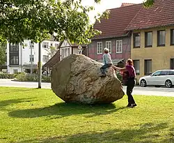 Findling mit Personen als Größenvergleich. An der linken Seite zu erkennen ist die Stelle, an der bei der Bergung ein Stück abgebrochen ist.