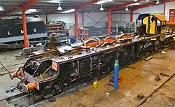 Blick in eine Werkshalle auf Rahmen und Fahrwerk einer Dampflokomotive