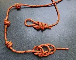 Franziskanerknoten als Gürtel und Zweistrang-Bändselknoten als Schlingenabschluss, alle sind 3-fache Überhandknoten